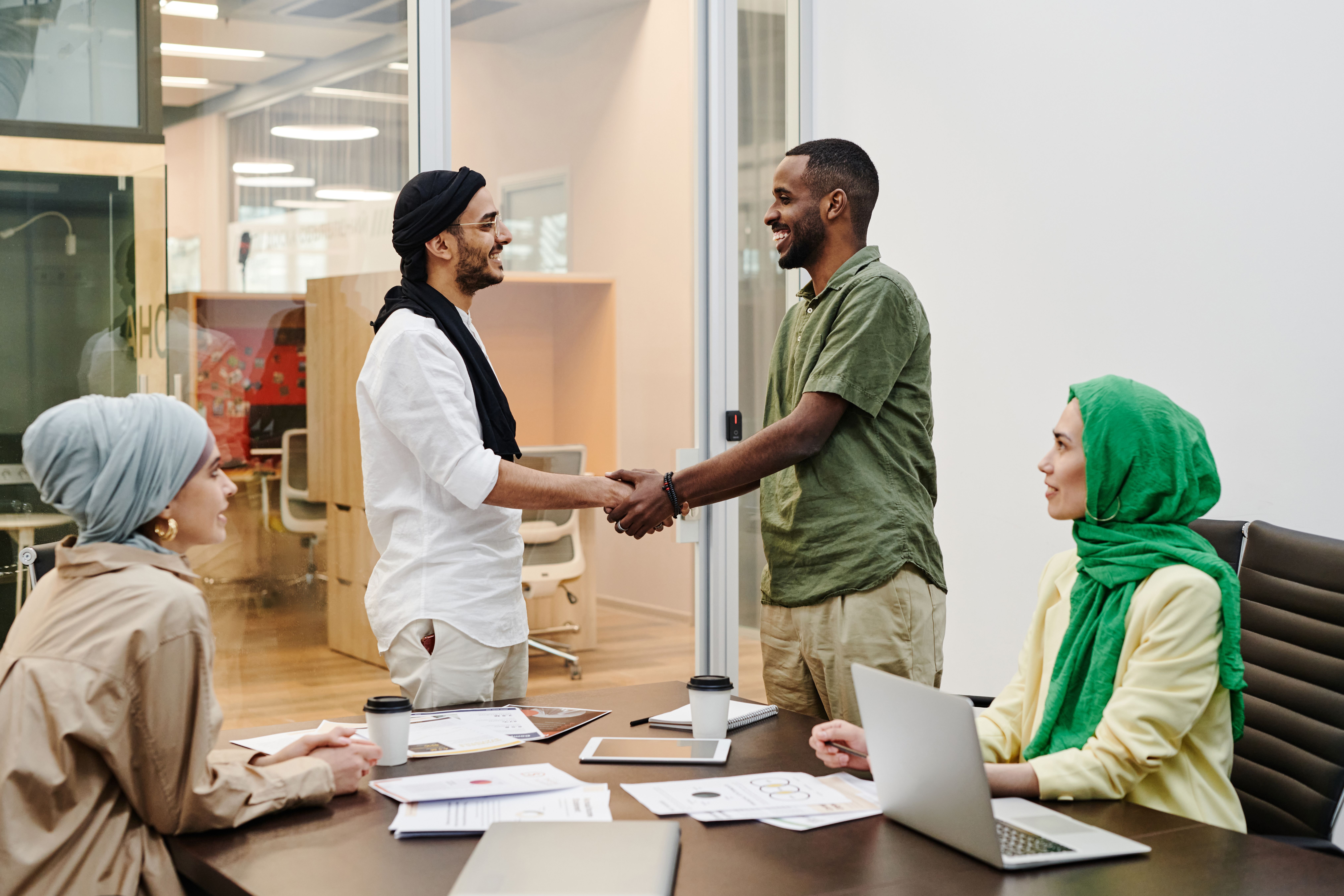 Professional handshake between diverse colleagues in a bright office meeting room, representing career growth and collaborative teamwork.